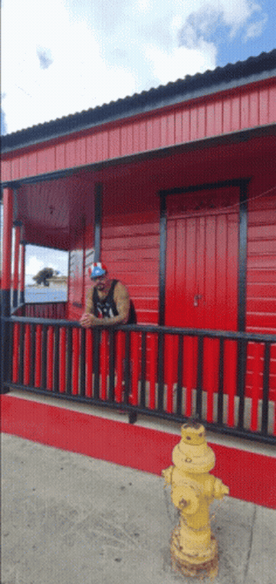 Man Leaning On Red Railing By Fire Hydrant GIF