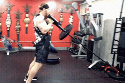 Man Lifting Barbell In Red Wall Gym GIF