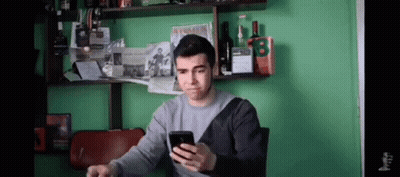 Man Looking At Phone By Green Wall GIF