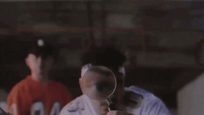 Man Looking Through Magnifying Glass At Another Man's Face GIF