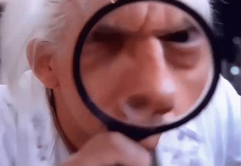 Man Looking Through Magnifying Glass At Face GIF