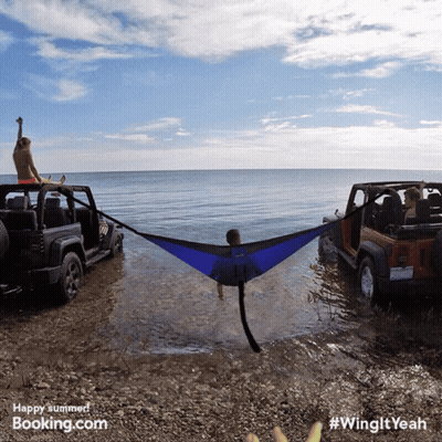 Man Lying In Hammock Between Two Jeep Wranglers On Beach GIF