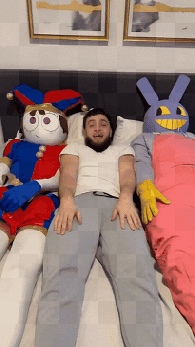 Man Lying On Bed Next To Stuffed Animals GIF