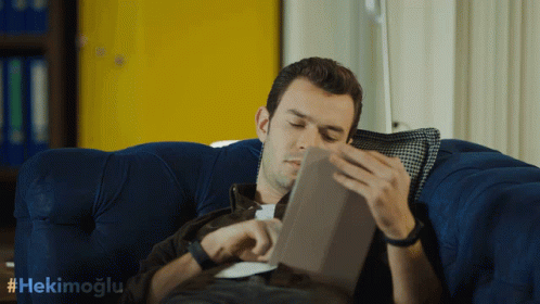 Man Lying On Blue Couch Reading Tablet GIF
