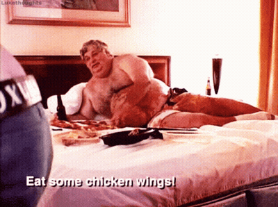 Man Lying Shirtless On Bed With Eat Chicken Wings GIF