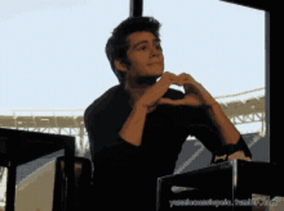 Man Making Heart Shape With Hands in Front of Window
