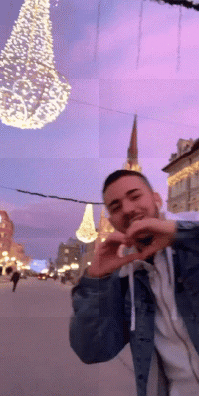 Man Making Heart With Hands In Front Of Christmas Tree GIF