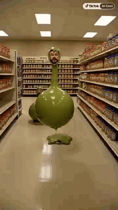 Man Next To Green Long-Neck Balloon In Grocery GIF