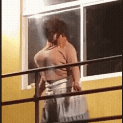 Man On Balcony Talking On Cell Phone GIF