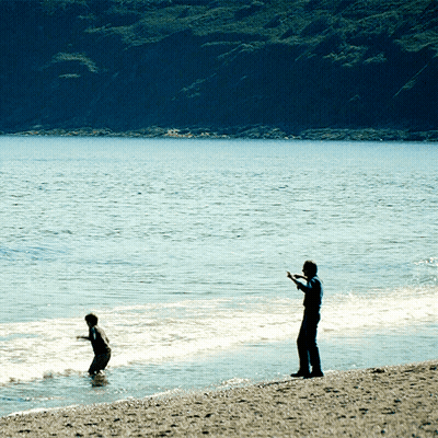 Man On Beach Watching Boy In Water GIF