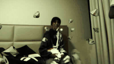 Man On Bed Surrounded By Papers Including Number 7 GIF