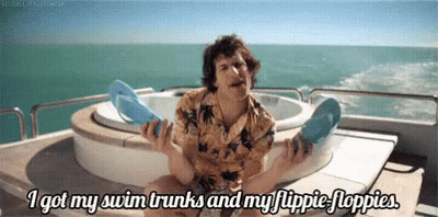 Man On Boat Holding Flip Flops Saying I Got My Swim Trunks GIF