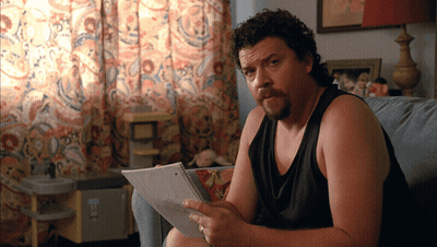 Man On Couch Holding Paper With Sticker Saying A GIF