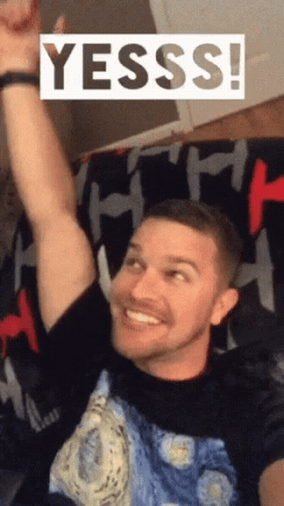 Man On Couch With Arm Up Saying Yesss GIF