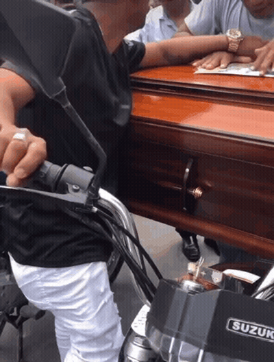 Man On Motorcycle Carrying Coffin With Suzuki Logo GIF