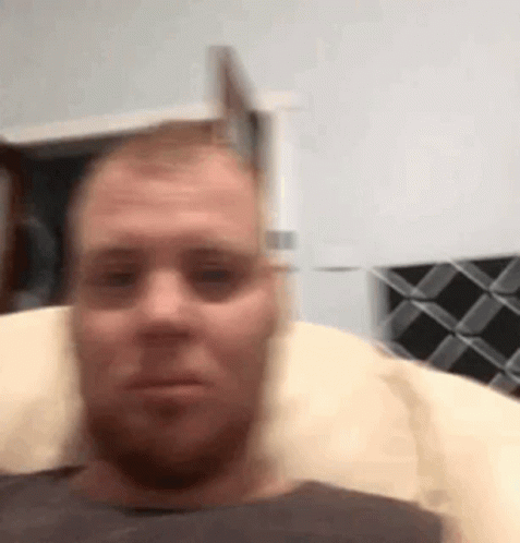 Man On Pillow In Chair Looking At Camera GIF