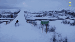 Man On Snowmobile Crossing Snowy Bridge GIF