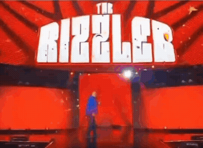 Man On Stage In Front Of Red Ripple Sign GIF
