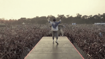 Man On Stage With Arms Outstretched Before Crowd GIF