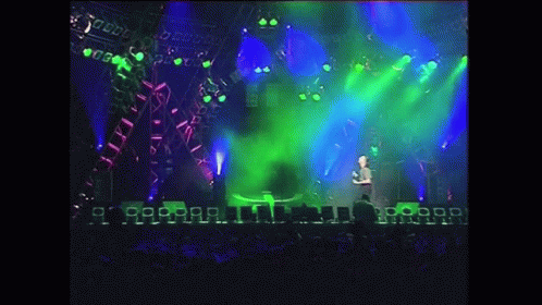 Man On Stage With Green Light And Crowd GIF