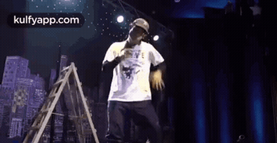 Man On Stage With Microphone And Ladder GIF
