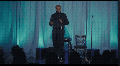 Man On Stage With Microphone In Front Of Crowd GIF