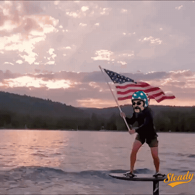 Man On Surfboard Holding American Flag GIF