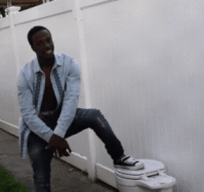 Man On Toilet Beside Fence GIF