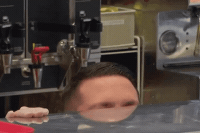 Man Peeking Over Counter With Reflection GIF
