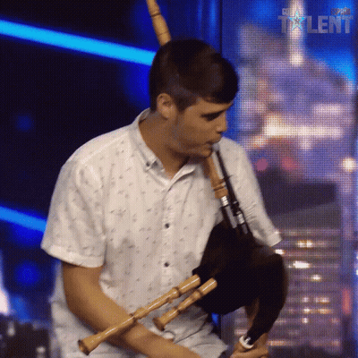 Man Playing Bagpipe In Front Of Super Talent Sign GIF