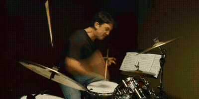 Man Playing Drum Set With Sheet Music GIF