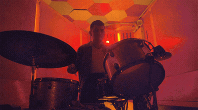 Man Playing Drums In Dark Room With Red Light GIF
