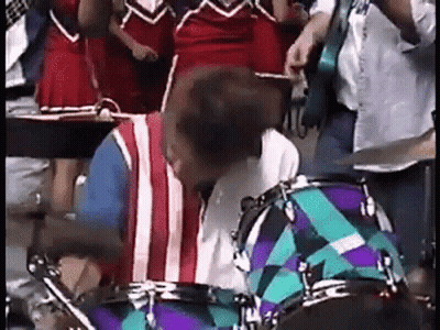 Man Playing Drums in Front of Cheerleader