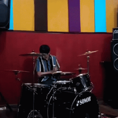 Man Playing Drums In Front Of Red Wall GIF