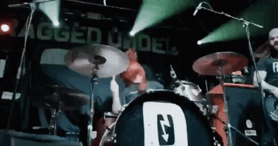 Man Playing Drums In Front Of Rugged Under Sign GIF