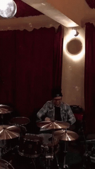 Man Playing Drums In Room With Red Curtains GIF