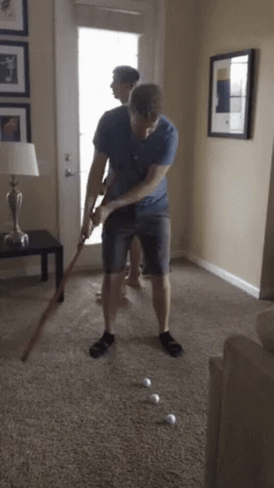 Man Playing Golf In Living Room While Another Watches GIF