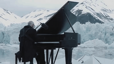 Man Playing Grand Piano In Front Of Snowy Glacier GIF