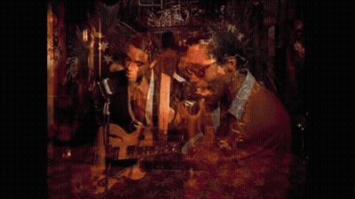 Man Playing Guitar And Singing Into Microphone While Another Man Looks On GIF