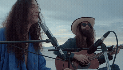 Man Playing Guitar And Woman Playing Drum In Desert GIF