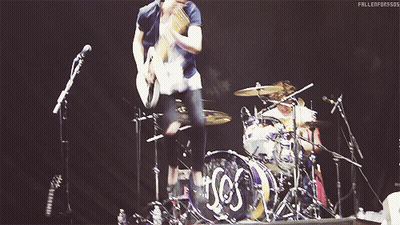 Man Playing Guitar In Front Of Drum Set Saying SOS GIF