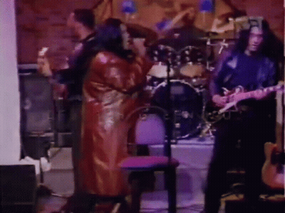 Man Playing Guitar In Front Of Drum Set With Woman Singing GIF