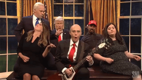 Man Playing Guitar in Front of Group With MAGA Hat