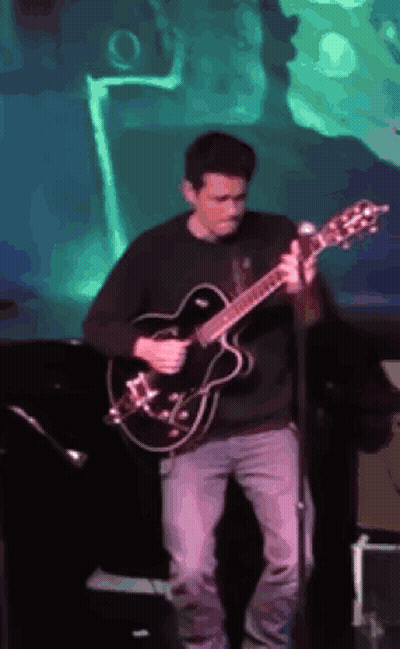 Man Playing Guitar On Stage With Green Background GIF