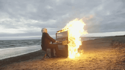 Man Playing Piano With Flames On Beach GIF