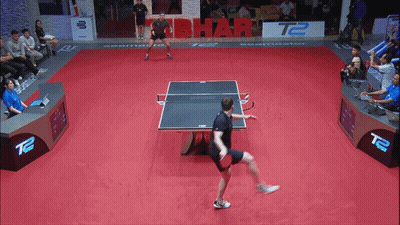Man Playing Ping Pong In Front Of T2 Sign GIF