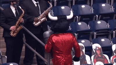 Man Playing Saxophone Next To Bull Mascot In Red Sequined Jacket GIF
