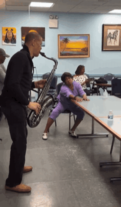 Man Playing Saxophone While Woman Sits On Table GIF