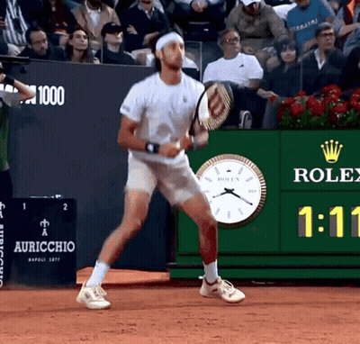 Man Playing Tennis In Front Of Rolex Clock GIF