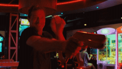 Man Playing Video Game In Dark Room With Claw Machine GIF